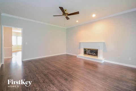A spacious room with a fireplace and a ceiling fan.