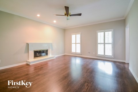 A spacious room with a fireplace and a ceiling fan.