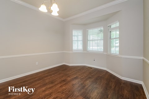 A room with wooden flooring and a window with blinds.