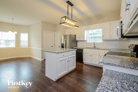 A kitchen with white cabinets and a granite countertop.