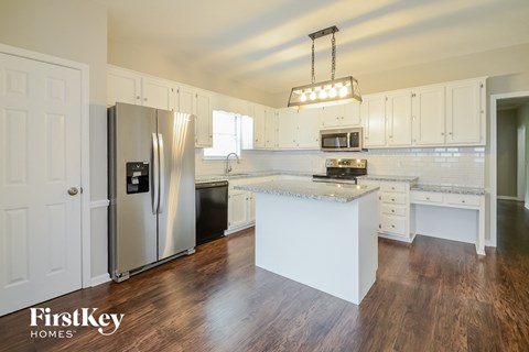 A kitchen with a refrigerator, microwave, oven, and sink.