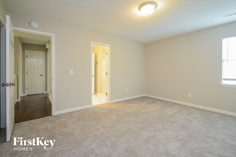 A carpeted room with a doorway leading to another room.