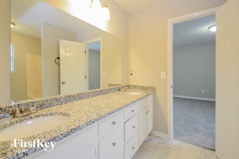 A bathroom with a granite countertop and a large mirror.