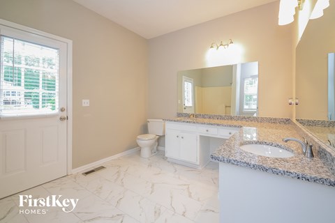 A bathroom with a marble counter top and a large mirror.
