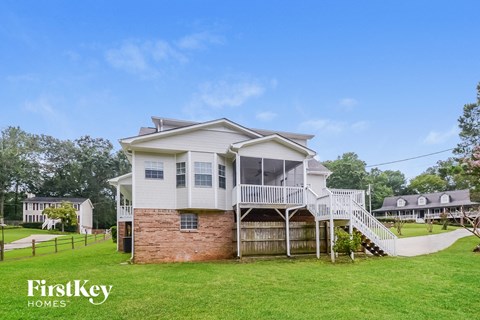 A house with a white porch and a brick base is for sale.