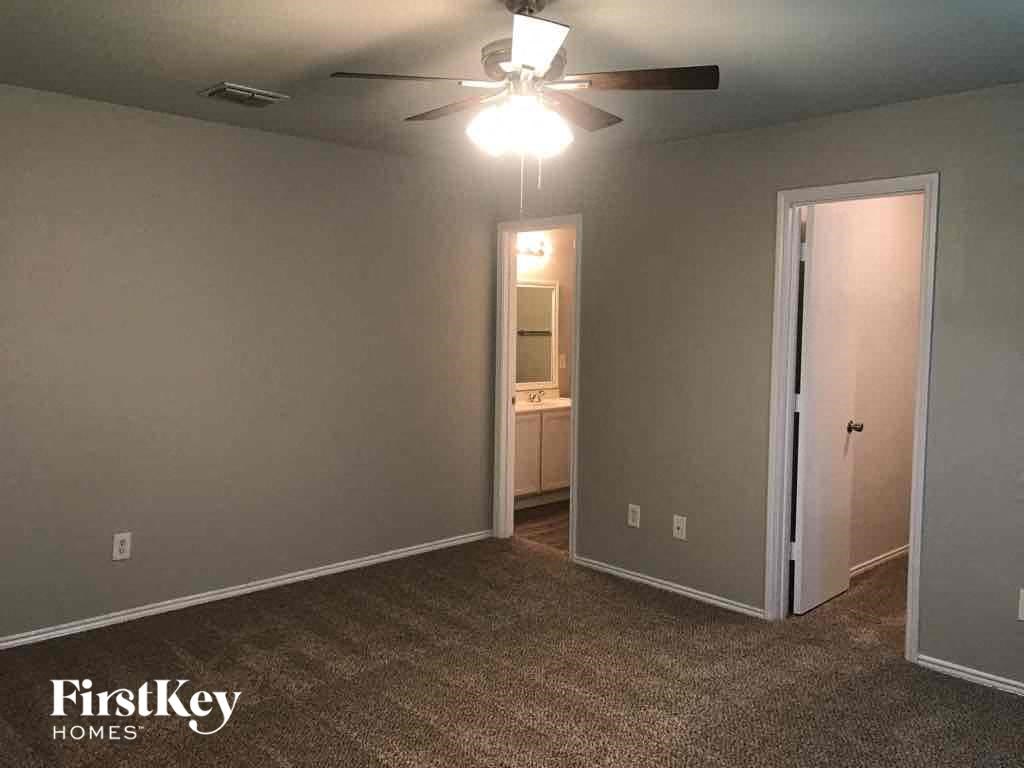 an empty living room with a ceiling fan and a door to a bathroom