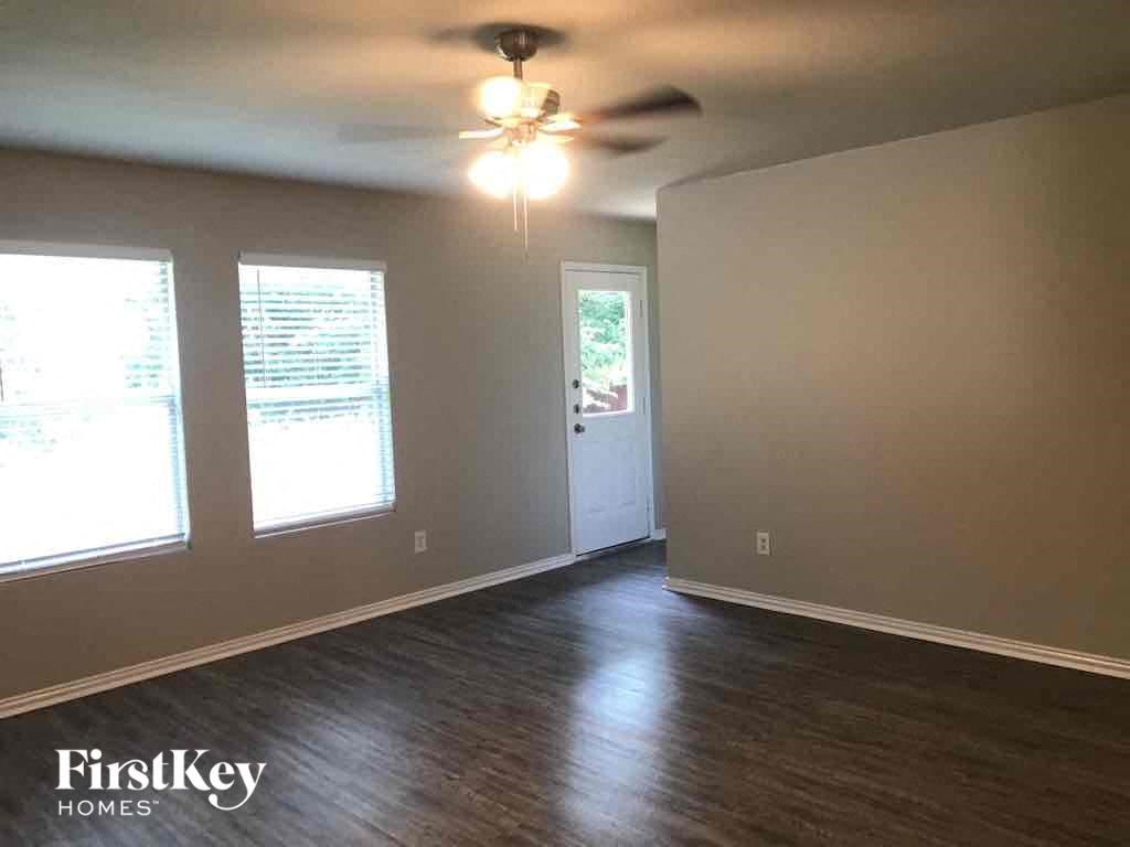 an empty living room with wood floors and a ceiling fan
