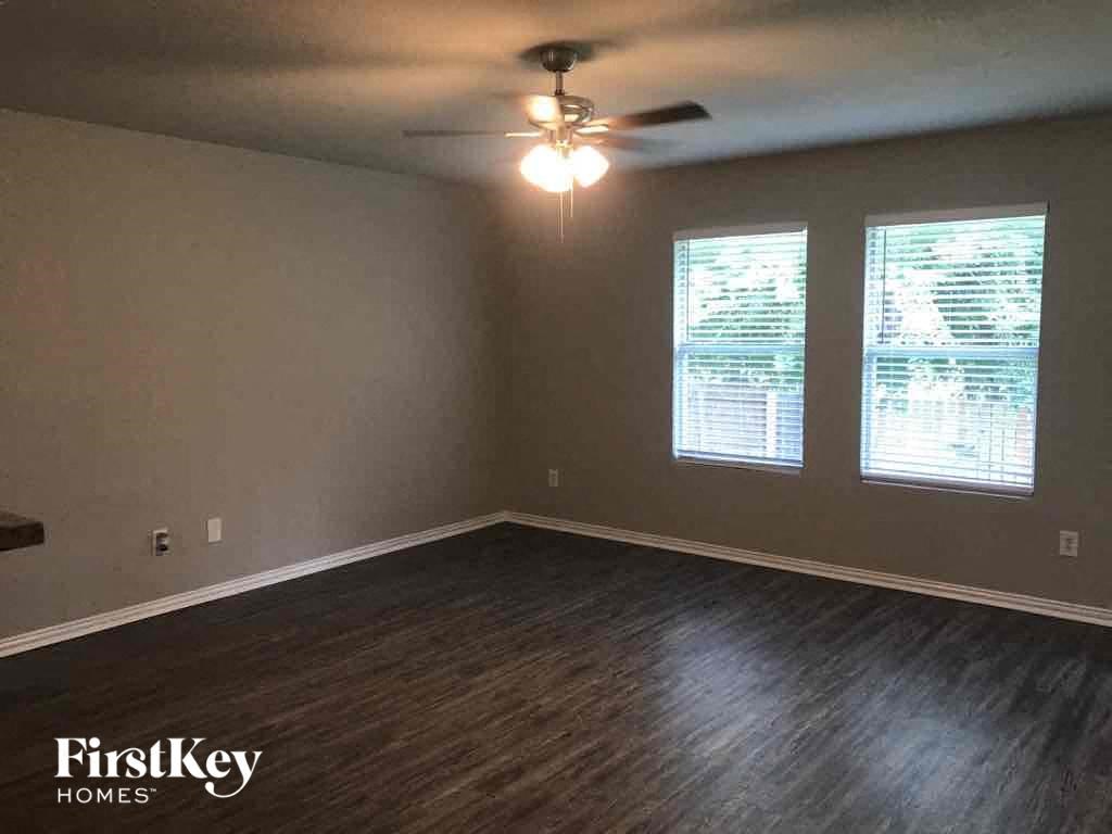 an empty living room with wood floors and a ceiling fan