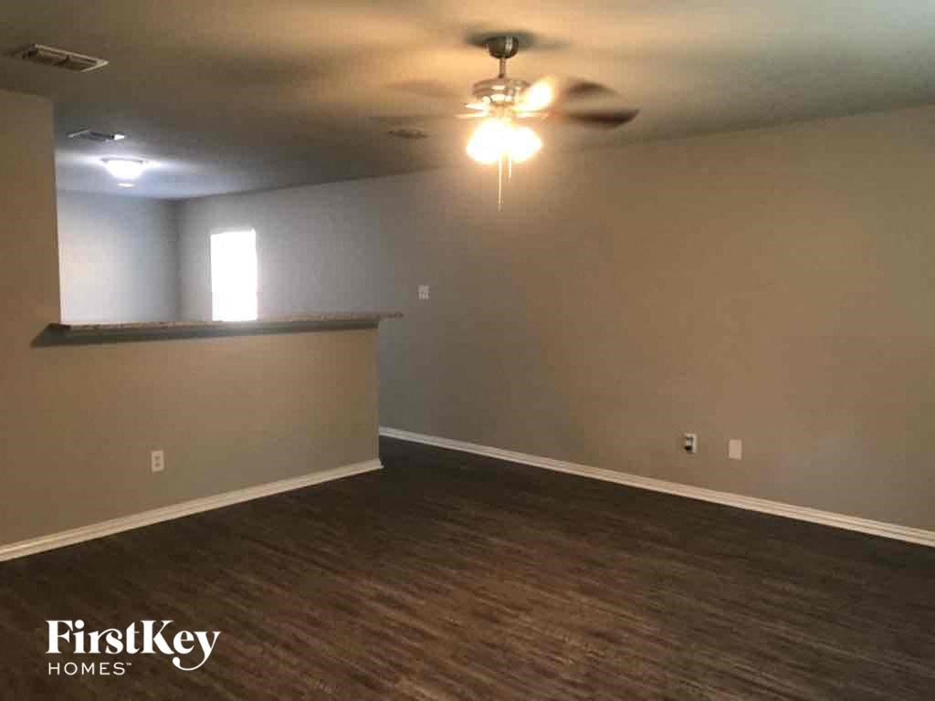 an empty living room with a ceiling fan