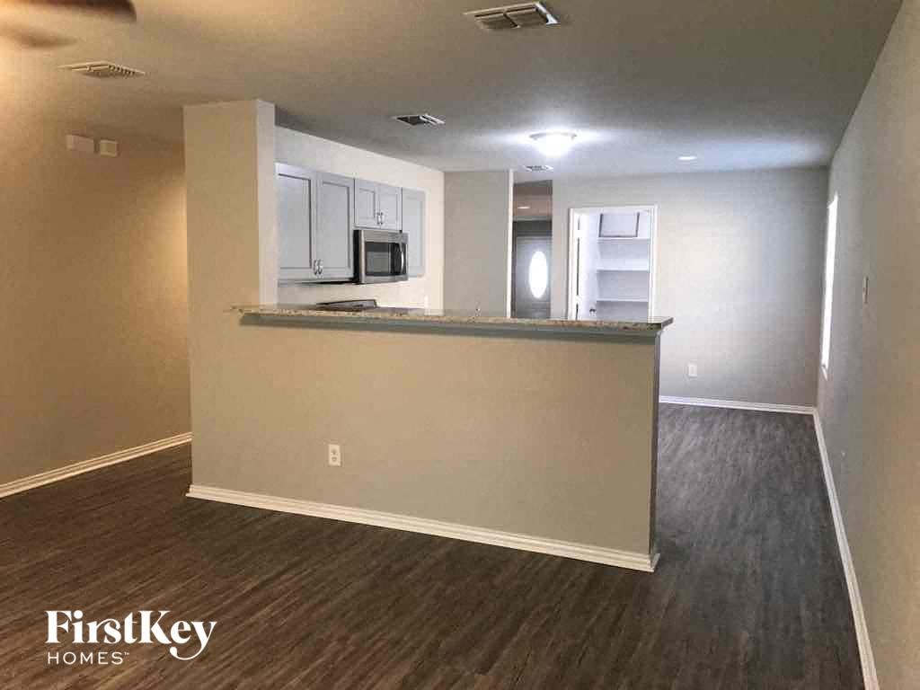 an empty living room with a counter and a kitchen