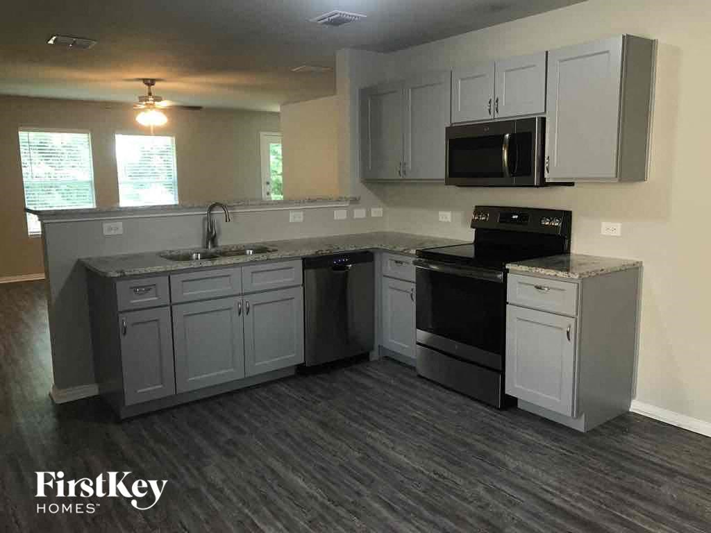an empty kitchen with white cabinets and black appliances