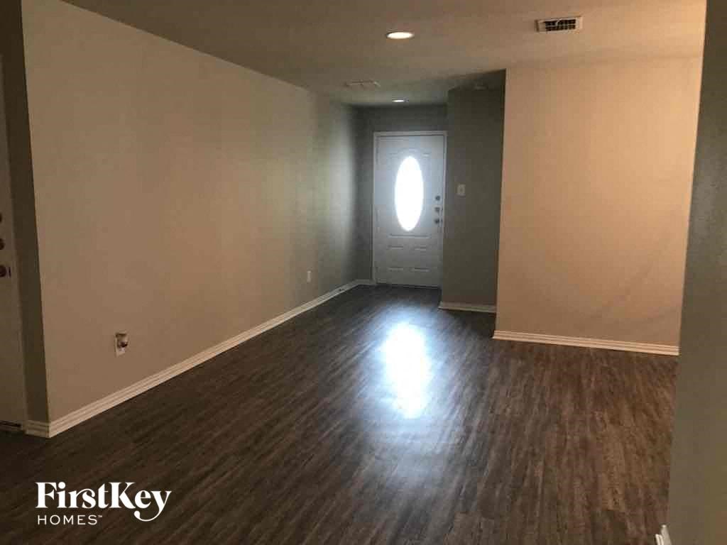 an empty living room with wood floors and a white door