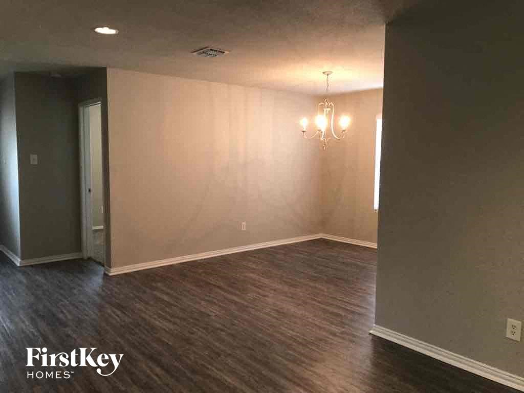 an empty living room with wood flooring and a chandelier