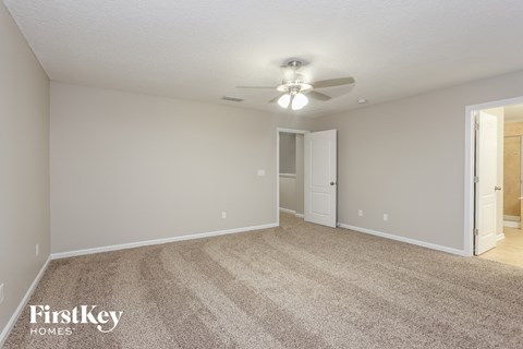 a spacious living room with carpet and a ceiling fan