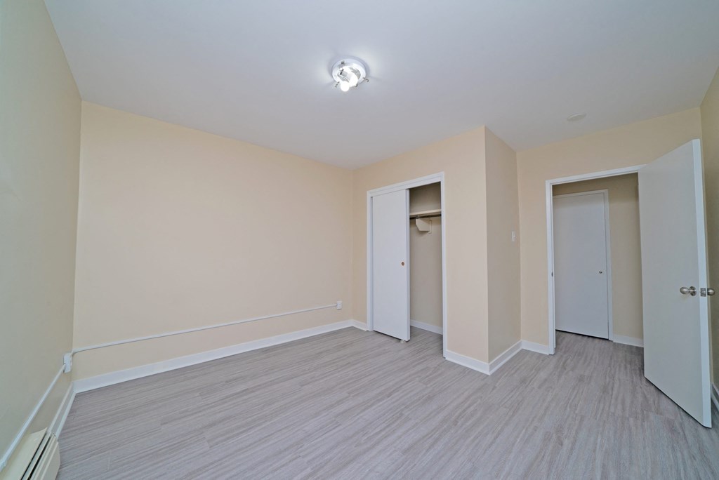 a living room with white walls and wood flooring and a door to a closet