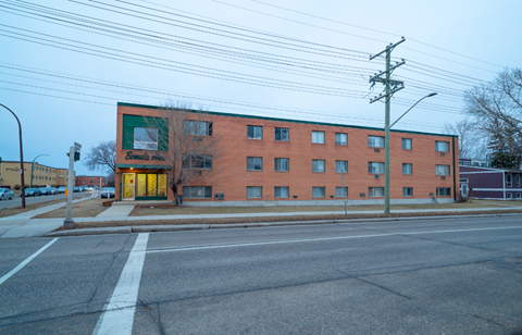 A red brick building with a green sign on the left side.