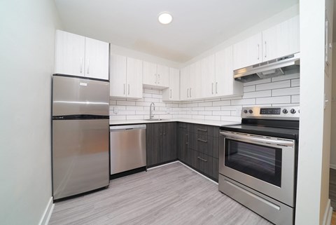 an empty kitchen with stainless steel appliances and white cabinets