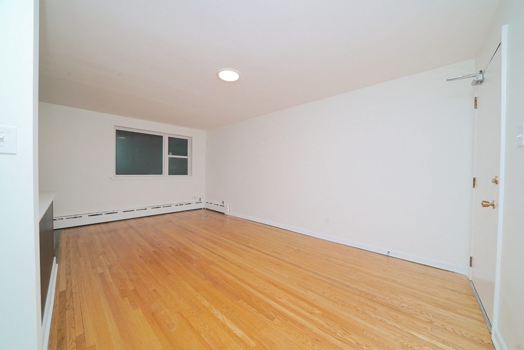 an empty room with wood floors and a window
