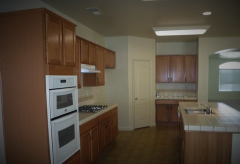 an empty kitchen with wooden cabinets and white appliances