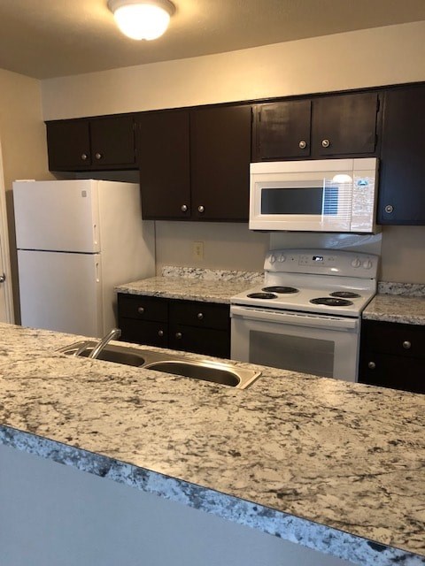 A kitchen with granite countertops and a white refrigerator.