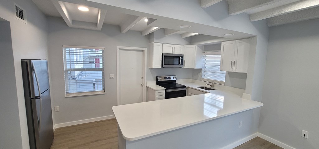 an empty kitchen with a white counter top and a refrigerator