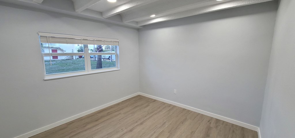 an empty room with a window and wood flooring
