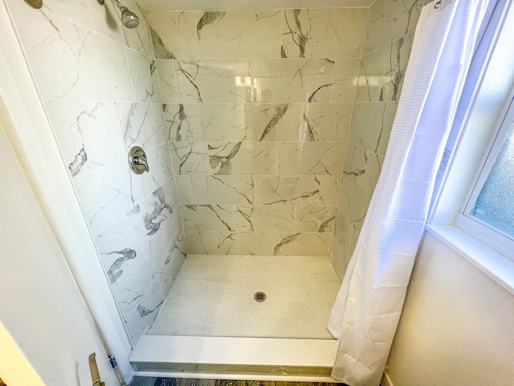 a small shower with marble tile and a window