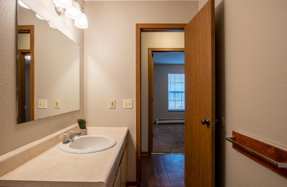 a bathroom with a sink and a mirror and a door to a hallway
