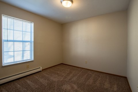 A room with a window and carpeted floor.