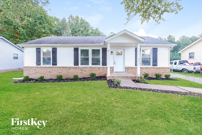 a small white house with a front lawn and a driveway