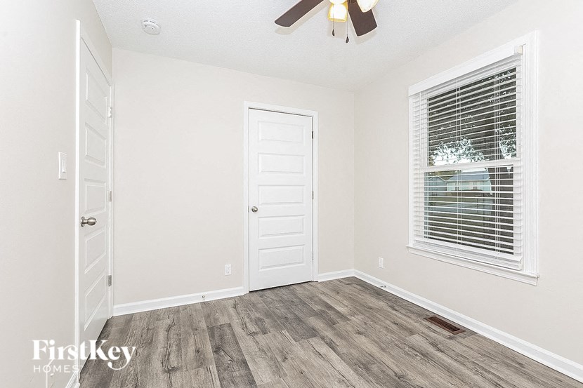 a bedroom with a closet and a window and a white door