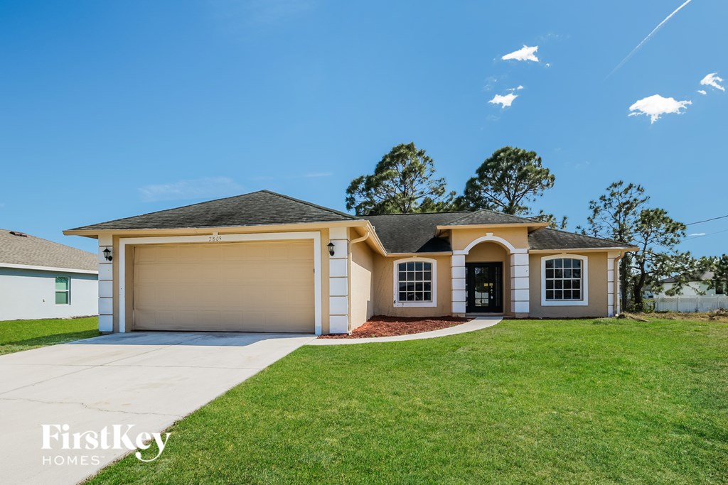 A house with a garage and a driveway in front of it.