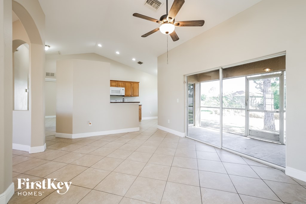 A spacious living room with a ceiling fan and sliding glass doors leading to a patio.