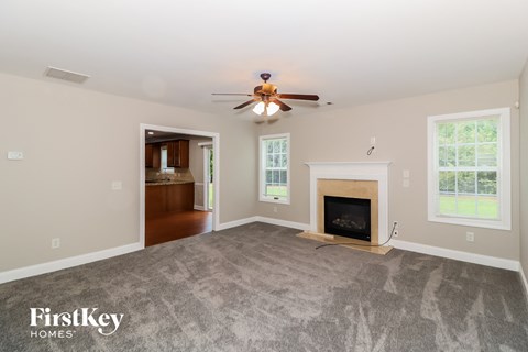 A spacious living room with a fireplace and a ceiling fan.
