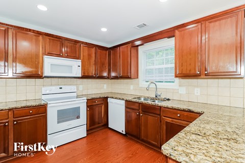A kitchen with wooden cabinets and a granite counter top.