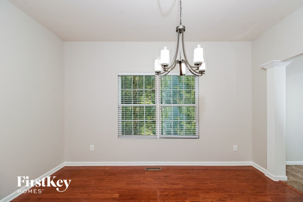 A room with a chandelier and a window with a green and white checkered curtain.