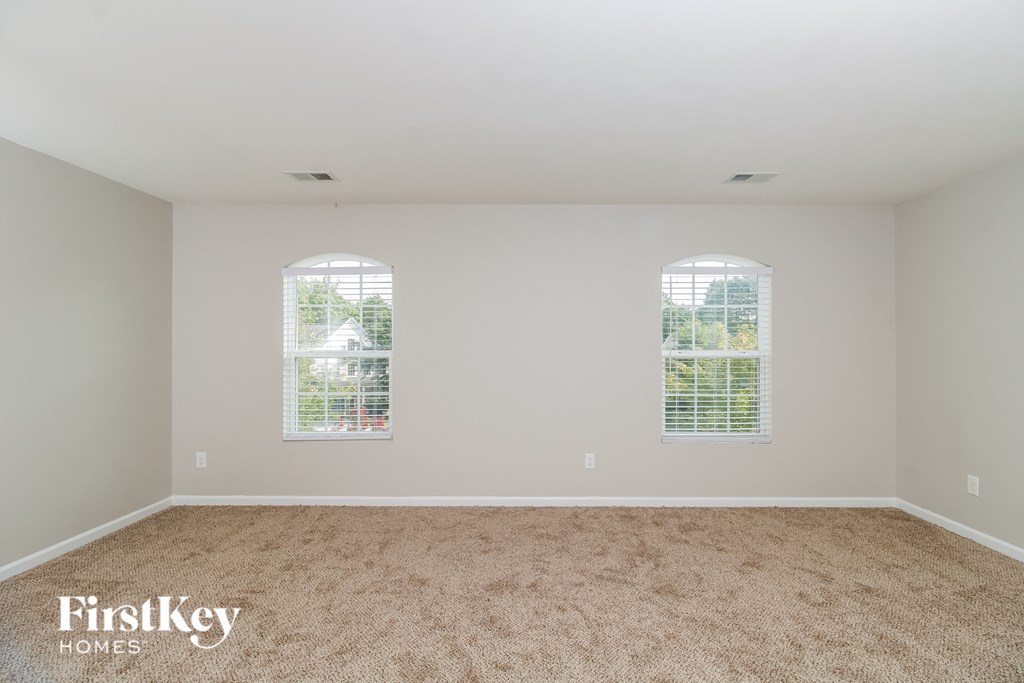 A room with two windows and a carpeted floor.