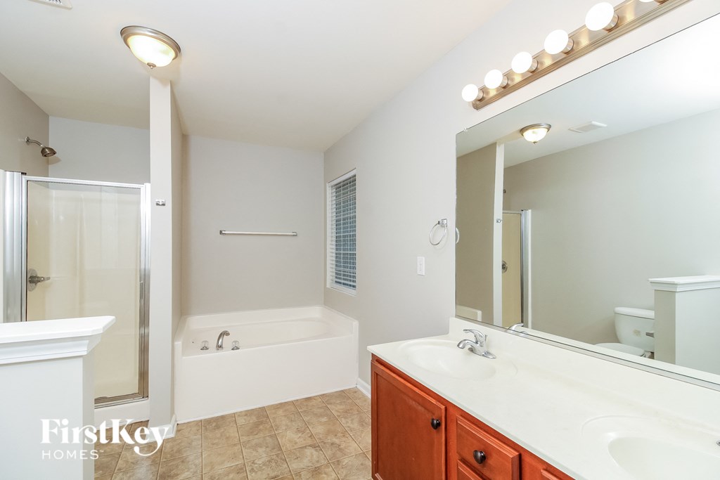 A bathroom with a tub, sink, and mirror.