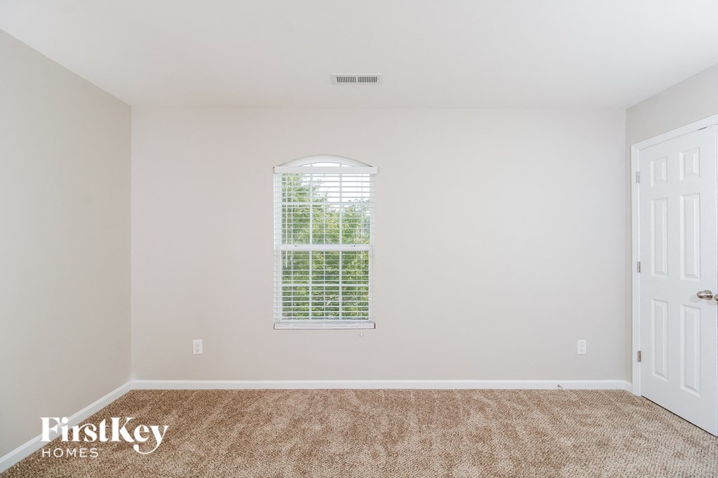 A room with a carpeted floor and a window with blinds.