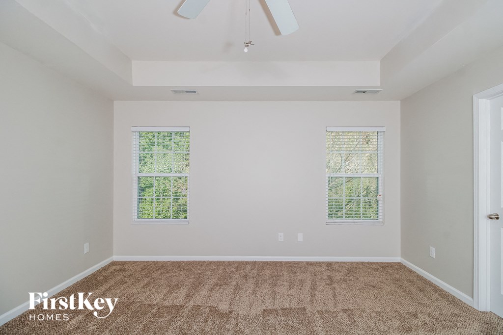 A room with a carpeted floor and two windows.