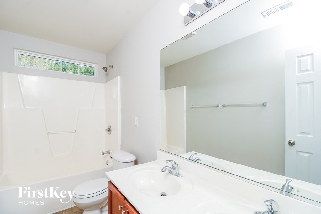 A white bathroom with a toilet, sink, and mirror.