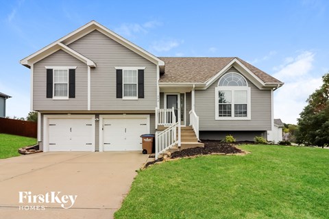 a gray house with a lawn and a driveway