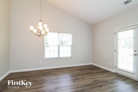 an empty living room with wood floors and a chandelier