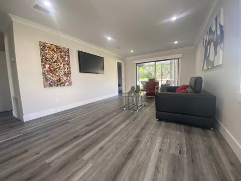 A living room with a grey couch and a television on the wall.