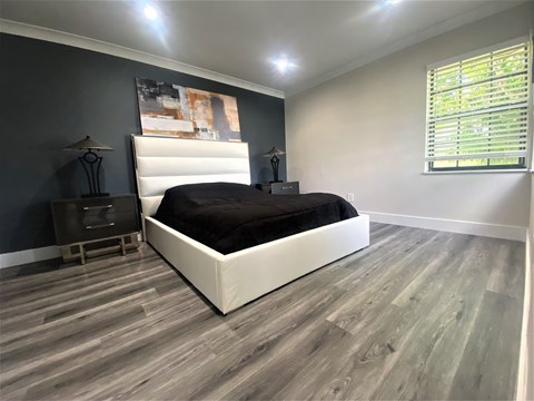 A bedroom with a large bed and a wooden floor.