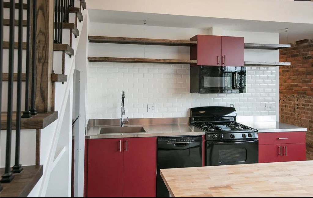 a kitchen with red cabinets and a stove and a sink