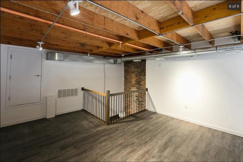 a room with a staircase and a white wall and wooden ceilings