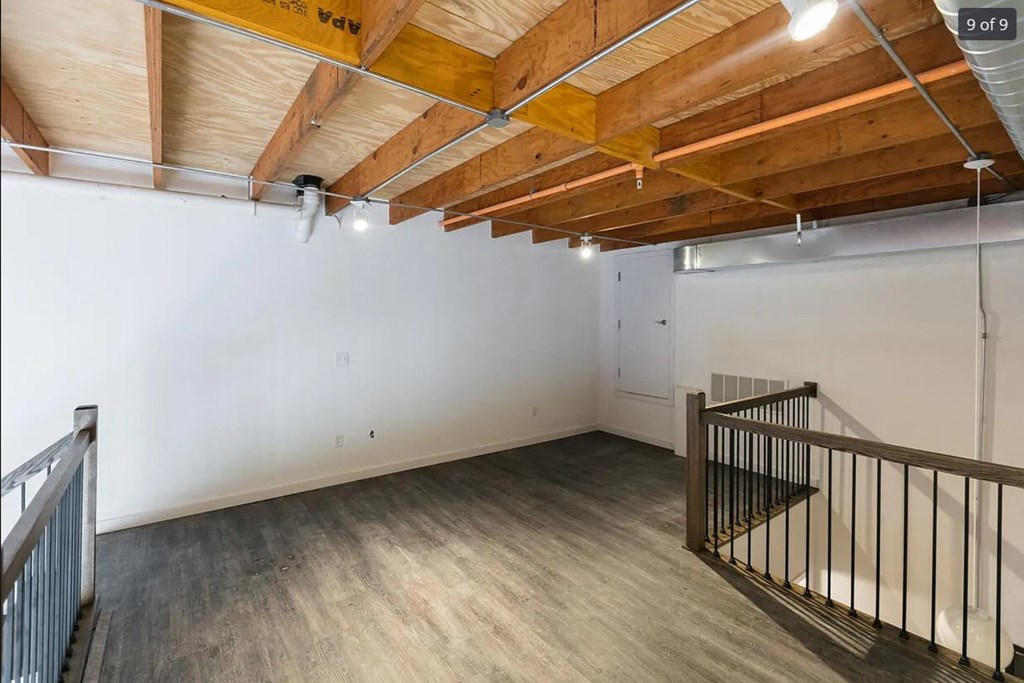 a large room with a staircase and a white wall and wooden ceilings