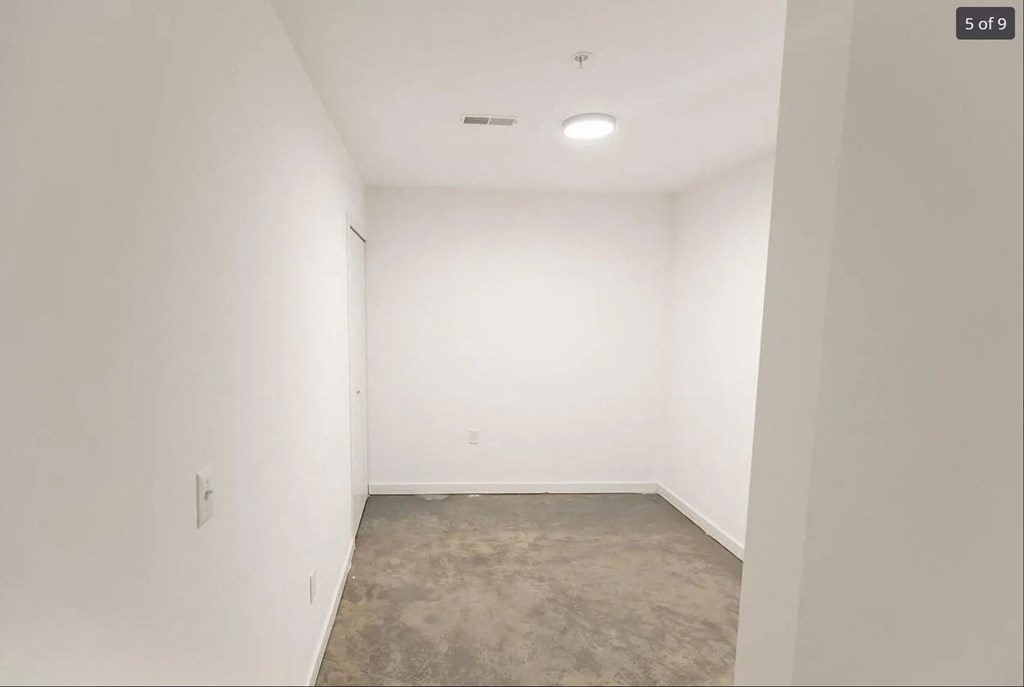 an empty room with white walls and a cement floor