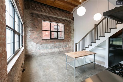 a living room with a table and a brick wall